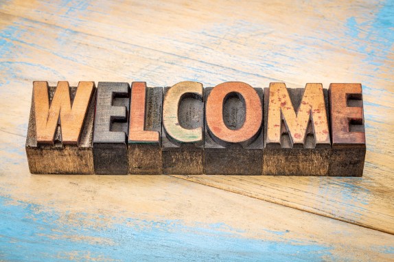 welcome word abstract - text in vintage letterpress wood type blocks stained by color inks against grunge painted wood